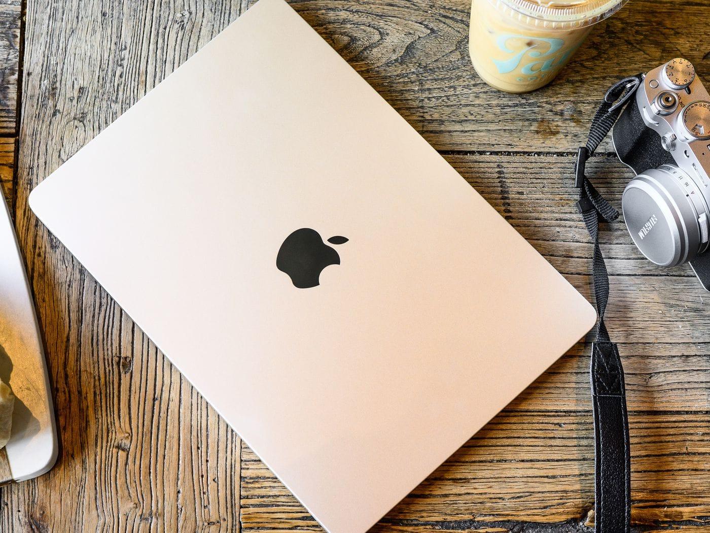 MacBook on table along with a camera lens